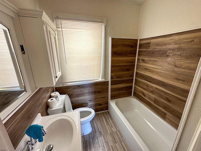 bathroom with toilet, a bathing tub, and sink