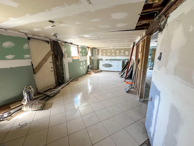 basement featuring washer / dryer and light tile patterned flooring