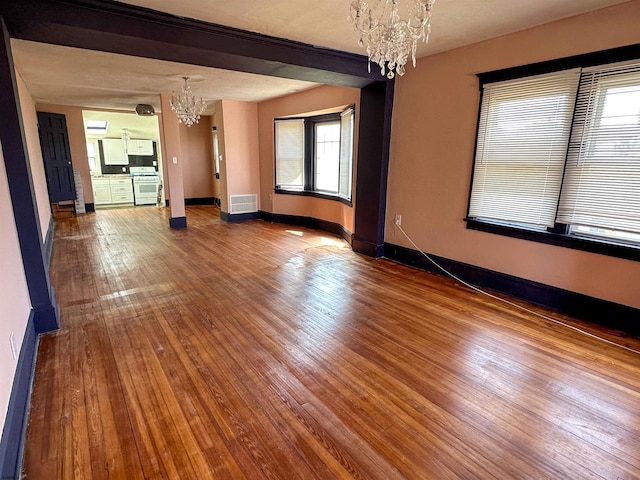 unfurnished room with an inviting chandelier, hardwood / wood-style floors, and a healthy amount of sunlight