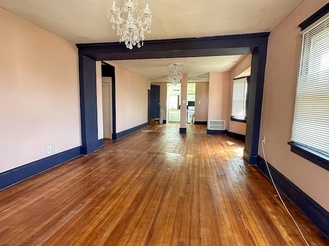 empty room featuring a chandelier and dark hardwood / wood-style floors