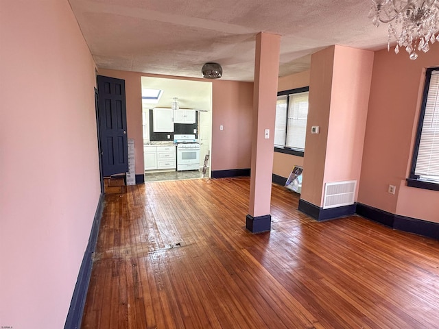 unfurnished living room with a textured ceiling, hardwood / wood-style floors, and a notable chandelier