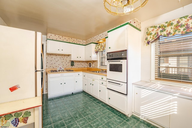 kitchen featuring white appliances, white cabinetry, and sink