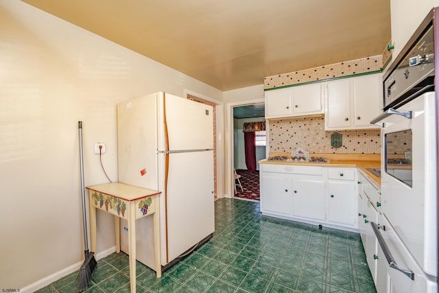 kitchen featuring white appliances, white cabinets, and tasteful backsplash