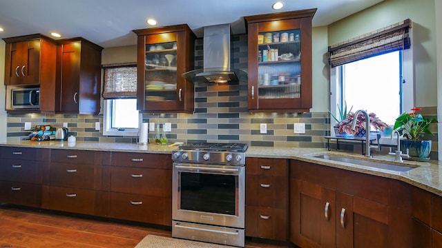 kitchen with dark wood-type flooring, wall chimney range hood, stainless steel appliances, tasteful backsplash, and sink