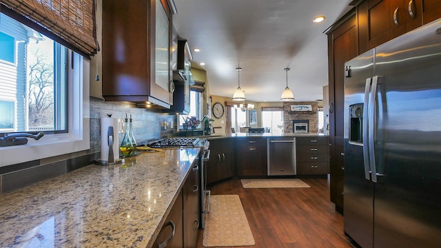 kitchen with decorative light fixtures, tasteful backsplash, light stone countertops, appliances with stainless steel finishes, and dark brown cabinets