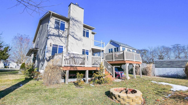 rear view of house featuring a deck, a lawn, and a fire pit