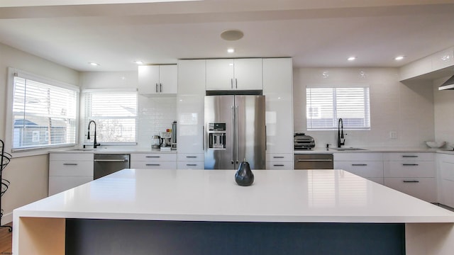 kitchen with a kitchen island, white cabinets, appliances with stainless steel finishes, and backsplash