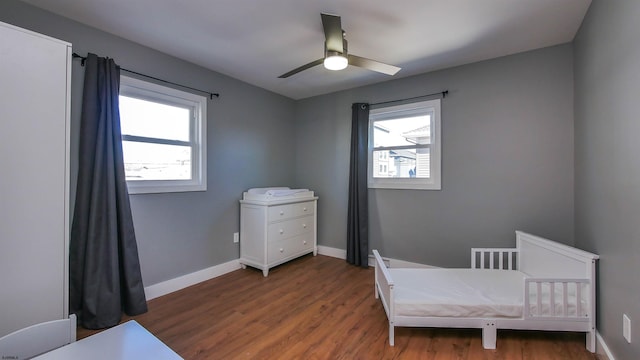 bedroom featuring ceiling fan, dark wood-type flooring, and multiple windows