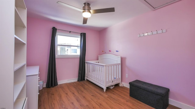 bedroom featuring a nursery area, ceiling fan, and light hardwood / wood-style floors