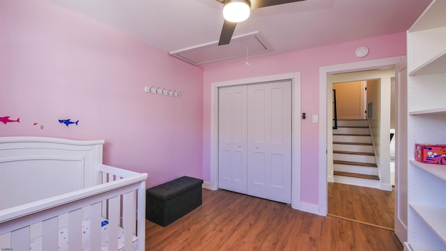 bedroom featuring a crib, hardwood / wood-style floors, a closet, and ceiling fan