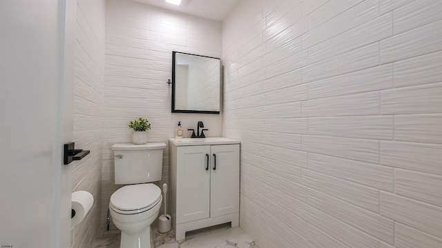 bathroom with toilet, vanity, and tile walls