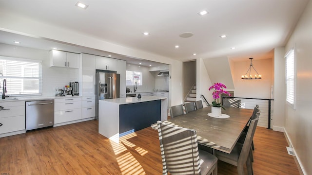 dining area featuring light wood-type flooring, a notable chandelier, and sink