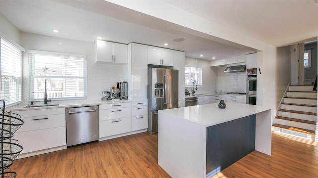 kitchen featuring sink, white cabinets, a center island, tasteful backsplash, and appliances with stainless steel finishes