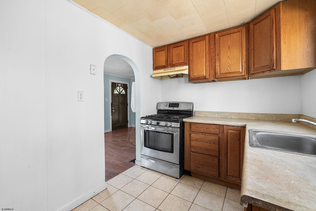 kitchen with light tile patterned floors, stainless steel range with gas cooktop, and sink