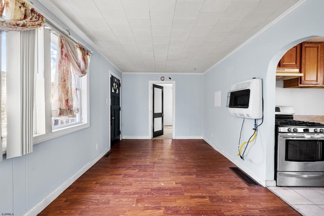 kitchen with hardwood / wood-style flooring, ornamental molding, heating unit, and stainless steel gas range