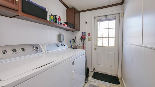 laundry area featuring a textured ceiling, ornamental molding, separate washer and dryer, and cabinets