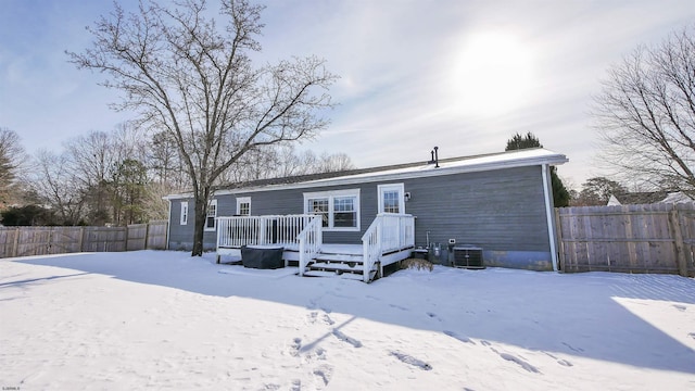 snow covered back of property featuring central air condition unit and a wooden deck