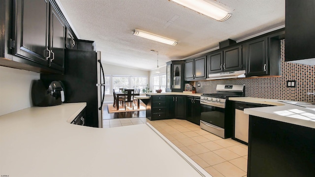 kitchen with stainless steel gas range oven, vaulted ceiling, light tile patterned floors, and a textured ceiling