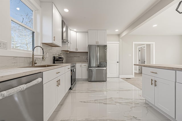 kitchen with sink, white cabinets, wall chimney exhaust hood, tasteful backsplash, and appliances with stainless steel finishes