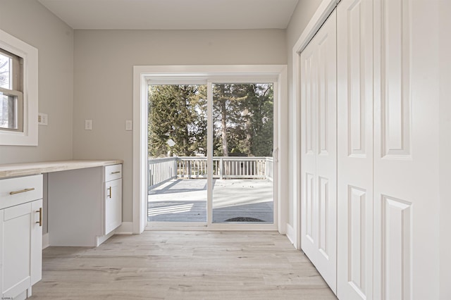 entryway with a healthy amount of sunlight, light wood-type flooring, and built in desk