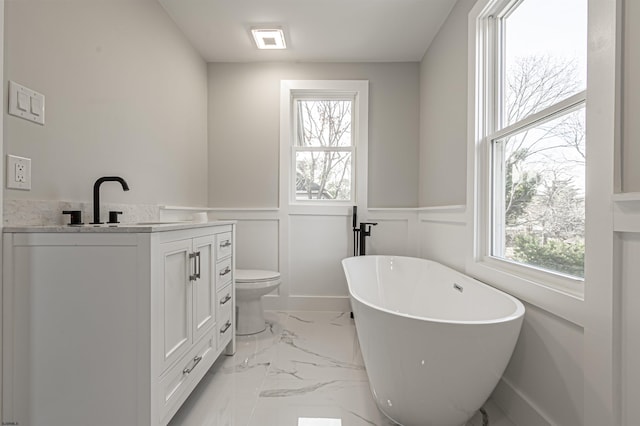 bathroom featuring toilet, vanity, and a tub to relax in