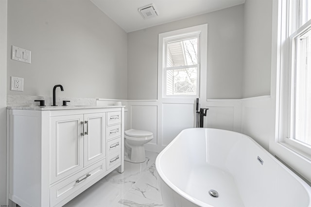 bathroom with a tub to relax in, vanity, and toilet