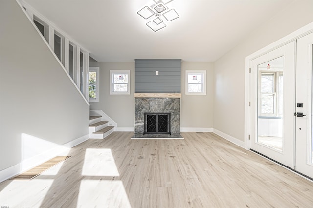 unfurnished living room featuring a premium fireplace and light hardwood / wood-style floors