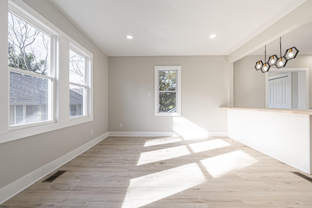 unfurnished room featuring light wood-type flooring, a chandelier, and plenty of natural light