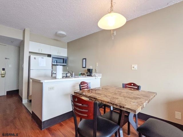 kitchen featuring a textured ceiling, pendant lighting, white cabinetry, and kitchen peninsula