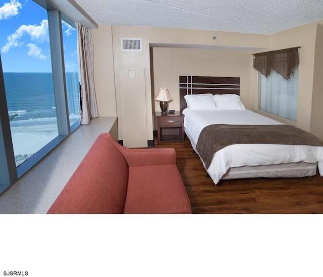 bedroom with a textured ceiling, multiple windows, access to outside, and a water view