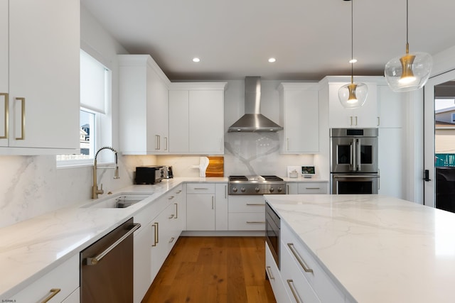 kitchen featuring white cabinets, appliances with stainless steel finishes, wall chimney exhaust hood, and sink