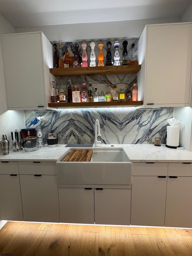 bar featuring light stone countertops, tasteful backsplash, and sink