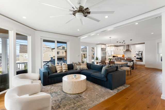 living room featuring light wood-type flooring, ceiling fan, and a healthy amount of sunlight