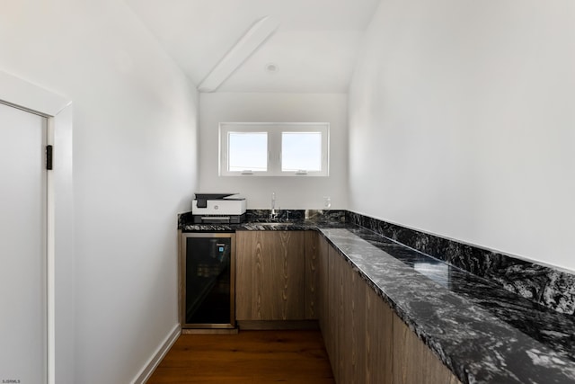 bar featuring sink, dark wood-type flooring, dark stone countertops, and wine cooler