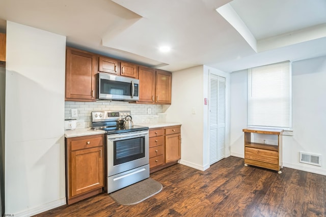 kitchen featuring stainless steel appliances, decorative backsplash, and dark hardwood / wood-style floors