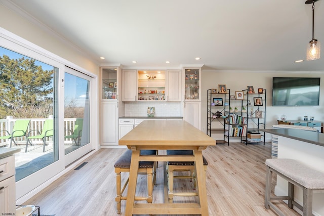 dining area featuring ornamental molding and light hardwood / wood-style floors