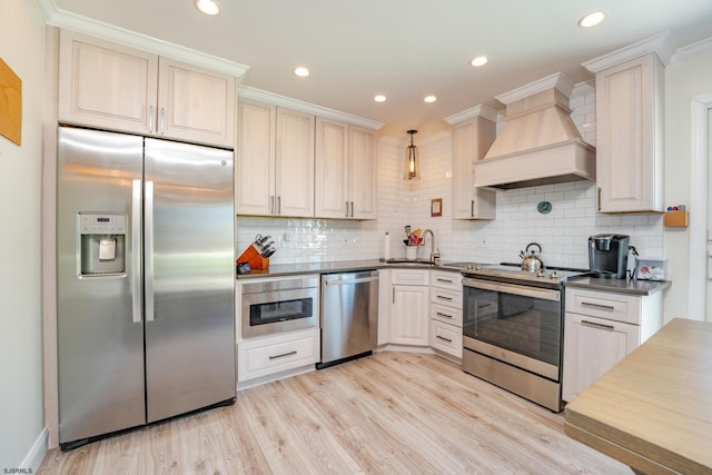 kitchen with appliances with stainless steel finishes, crown molding, custom range hood, decorative backsplash, and decorative light fixtures