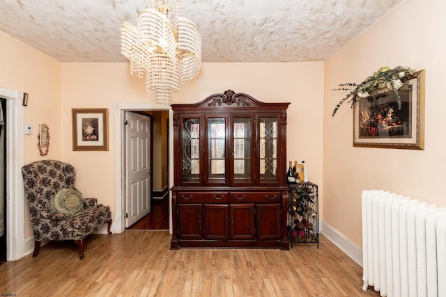 interior space featuring a notable chandelier, light hardwood / wood-style flooring, and radiator heating unit