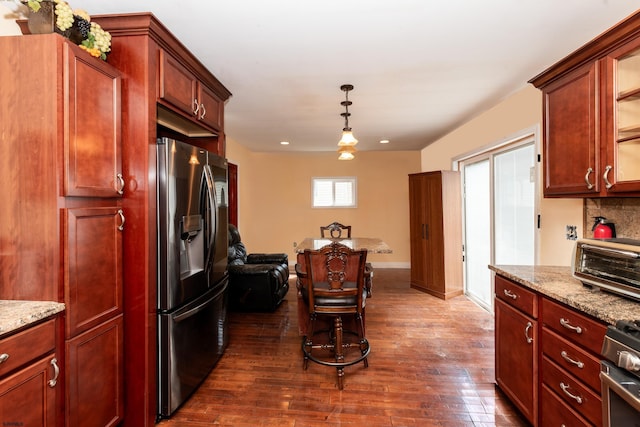 kitchen with light stone counters, dark hardwood / wood-style floors, decorative light fixtures, decorative backsplash, and appliances with stainless steel finishes