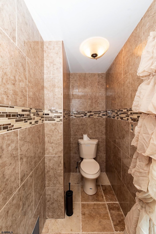 bathroom featuring tile walls and toilet