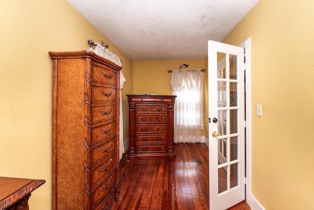 hallway featuring a textured ceiling, dark wood-type flooring, and french doors