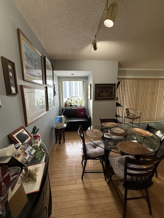 dining area with a textured ceiling and light hardwood / wood-style flooring