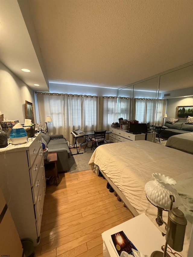 bedroom with a textured ceiling and light hardwood / wood-style flooring