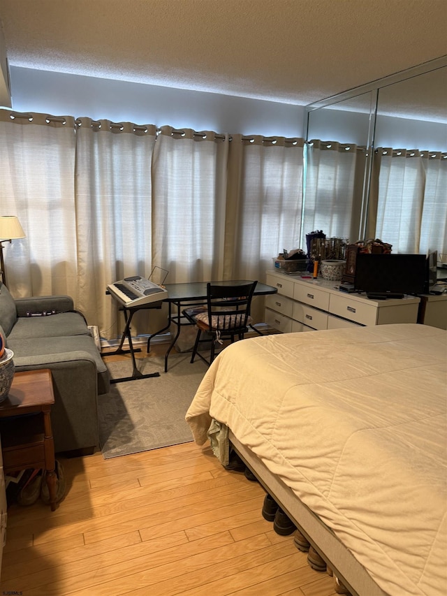 bedroom with light wood-type flooring and a textured ceiling