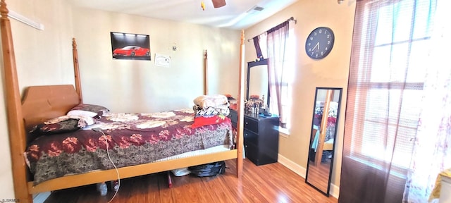 bedroom with ceiling fan, multiple windows, and hardwood / wood-style flooring