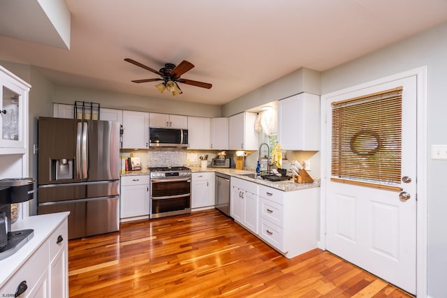 kitchen featuring light hardwood / wood-style floors, backsplash, white cabinetry, appliances with stainless steel finishes, and sink