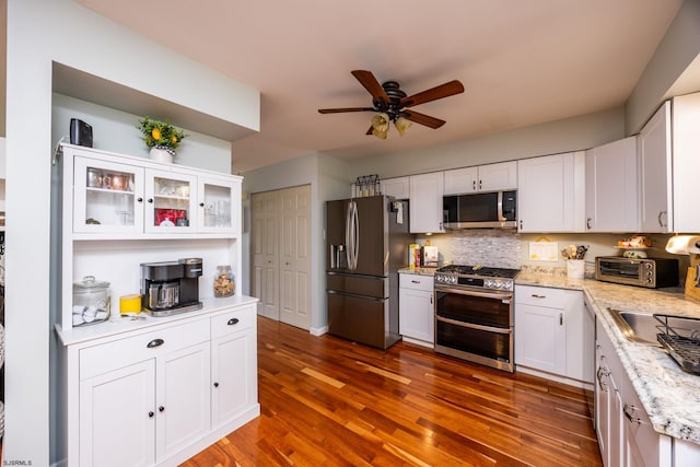 kitchen featuring stainless steel appliances, ceiling fan, dark wood-type flooring, white cabinets, and tasteful backsplash