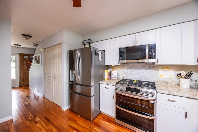 kitchen with stainless steel appliances, white cabinetry, and wood-type flooring