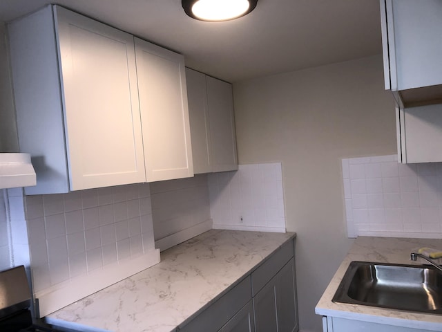 kitchen featuring extractor fan, decorative backsplash, white cabinets, stove, and sink