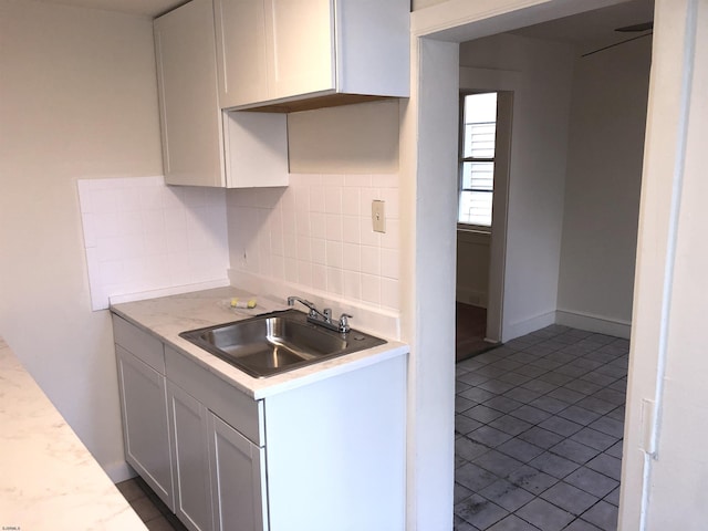 kitchen with sink, tile patterned floors, white cabinets, and decorative backsplash